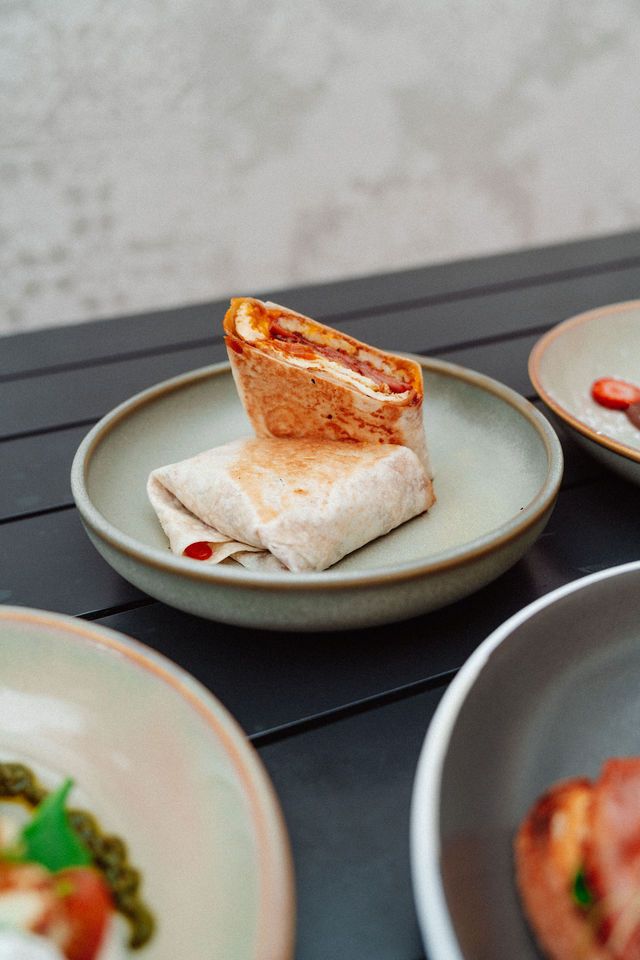 A burrito is sitting on a plate on a table.