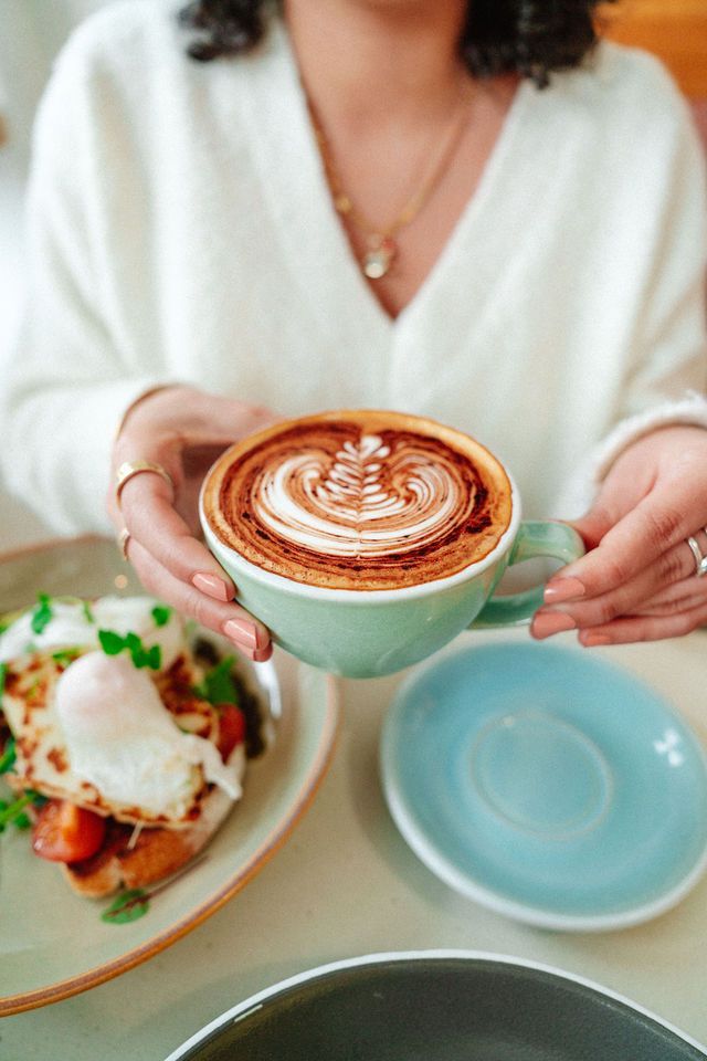 A woman is sitting at a table holding a cup of coffee.