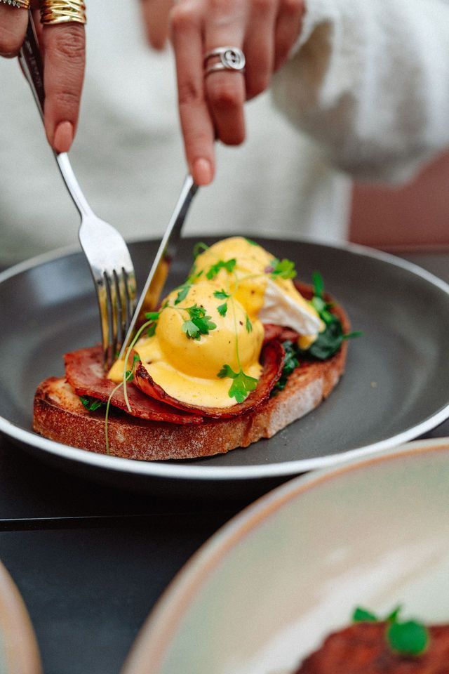 A person is cutting a piece of food with a fork on a plate.