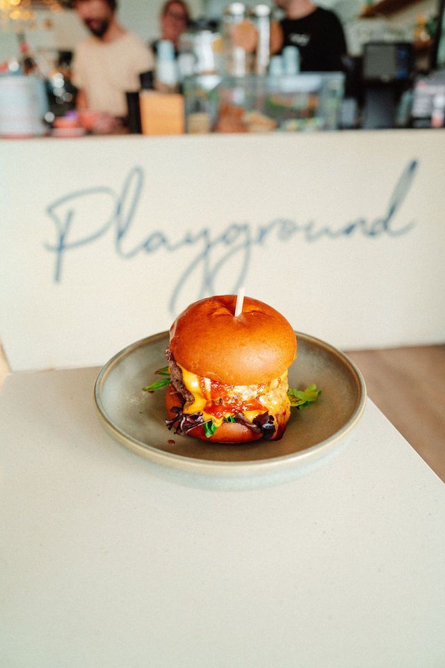 A hamburger with a candle in it is on a plate on a table.