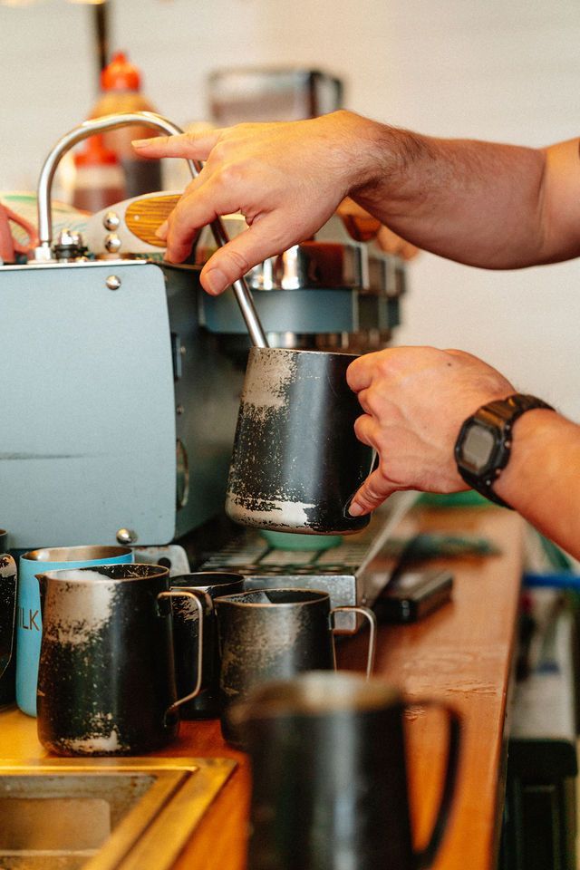 A person is pouring milk into a cup of coffee.