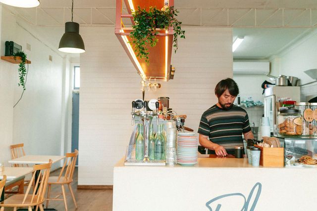 A man is standing behind a counter in a restaurant.