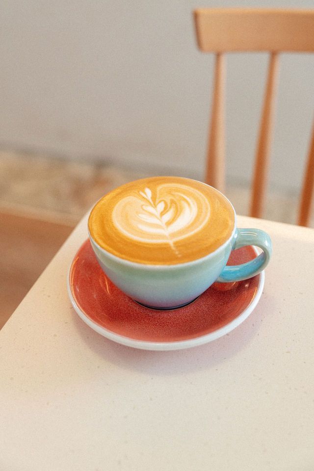 A cup of cappuccino on a saucer on a table.