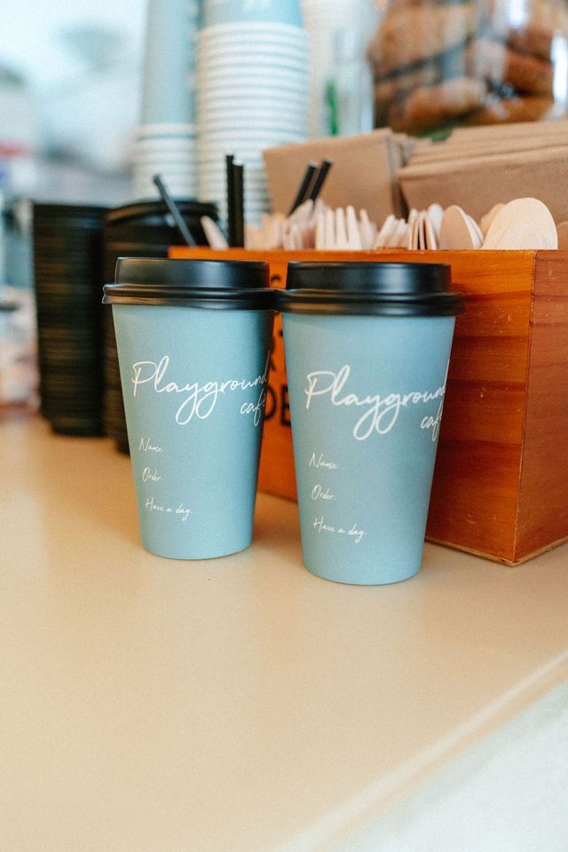 Two coffee cups are sitting on a counter next to a wooden box.