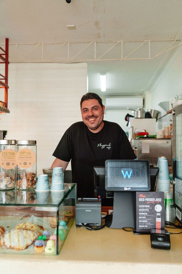 A man is standing behind a counter in a restaurant.