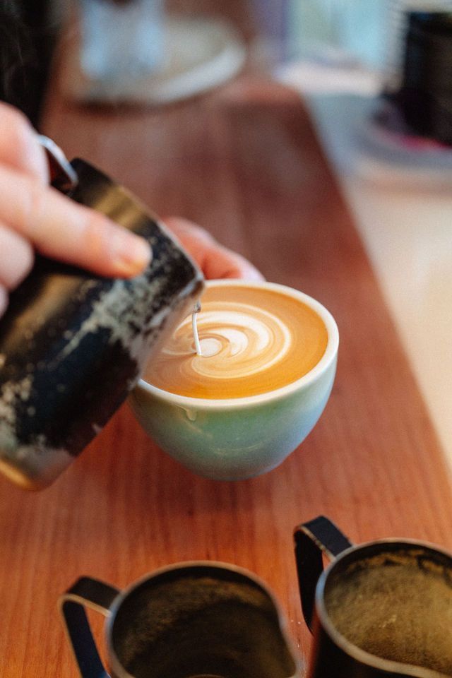 A person is pouring milk into a cup of coffee.