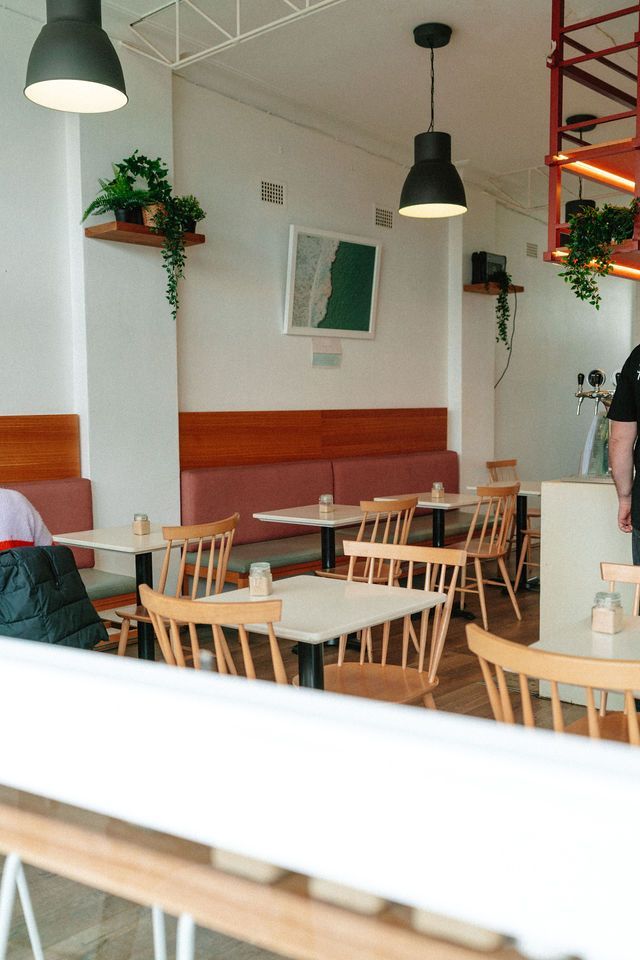 A restaurant with tables and chairs and a man standing in the background.