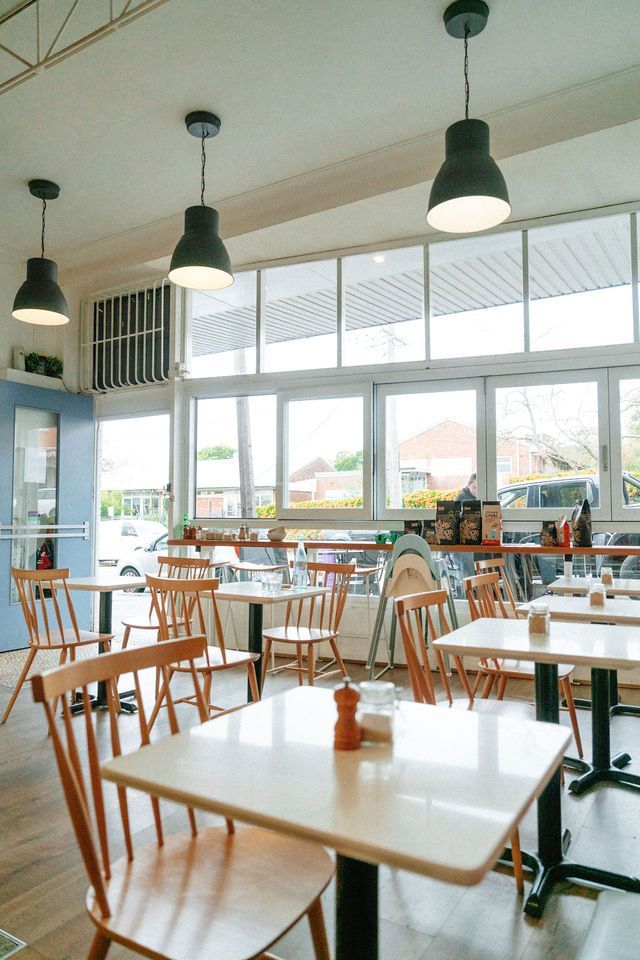 A restaurant with tables and chairs and a lot of windows.
