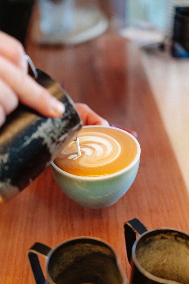 A person is pouring milk into a cup of coffee.