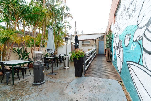 A patio with tables and chairs and a mural on the wall.