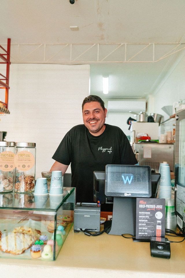 A man is standing behind a counter in a restaurant.