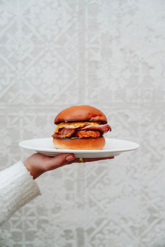 A person is holding a plate with a sandwich on it.