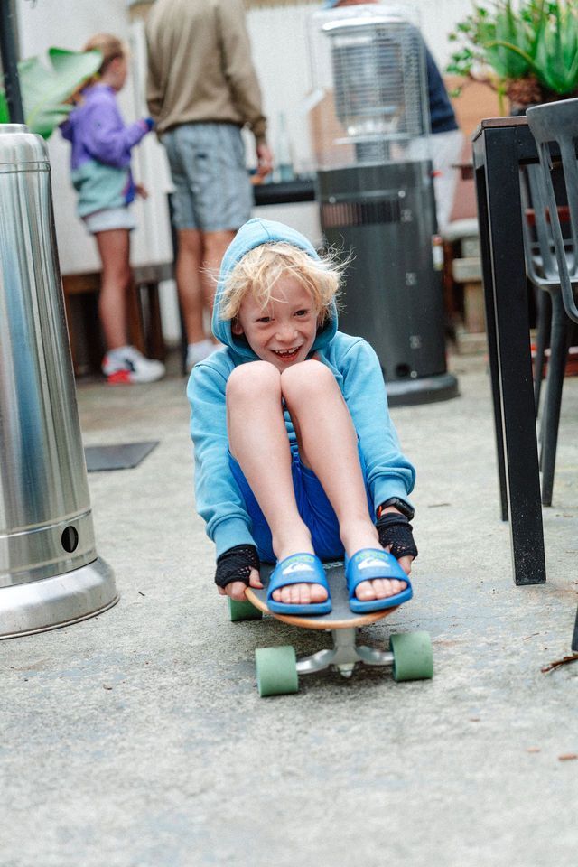 A young boy is riding a skateboard on a patio.