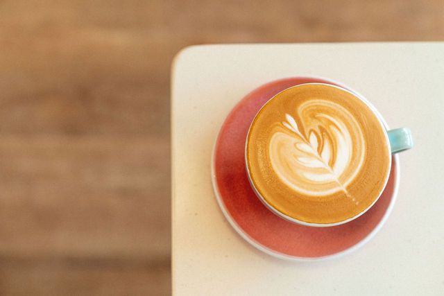 A cup of cappuccino on a saucer on a table.