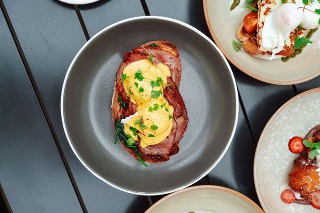A bowl of food is sitting on a table next to plates of food.