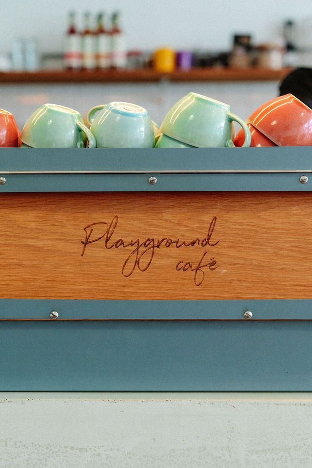 A wooden box filled with coffee cups in a playground cafe.