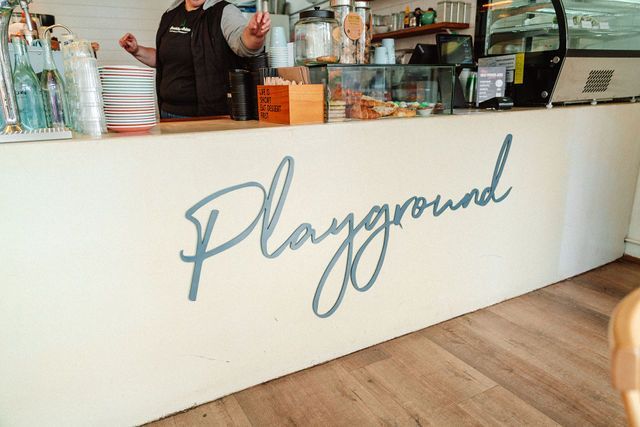 A man is standing behind a counter with the word playground written on it.