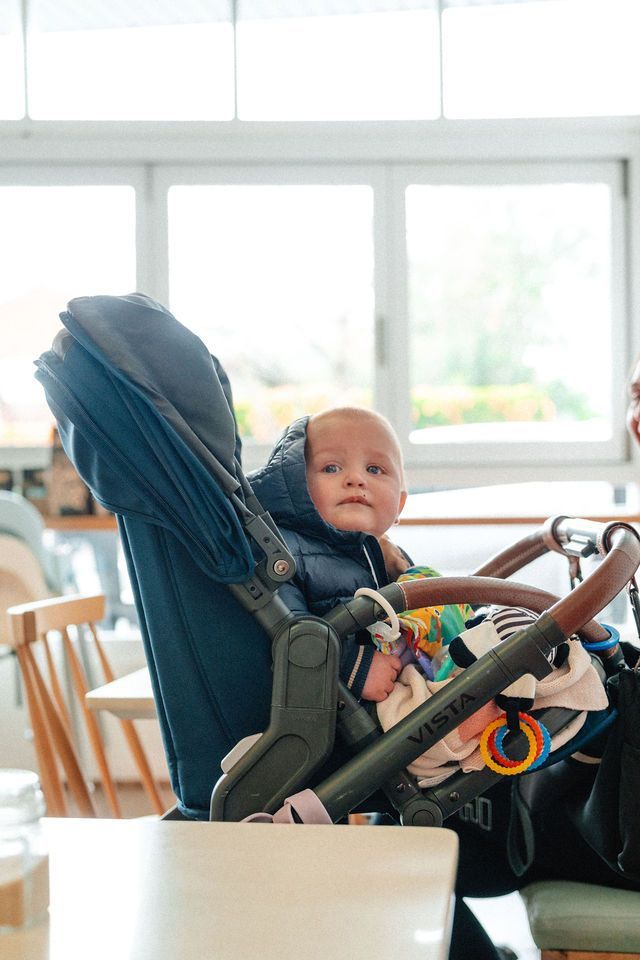 A baby is sitting in a stroller on a table.