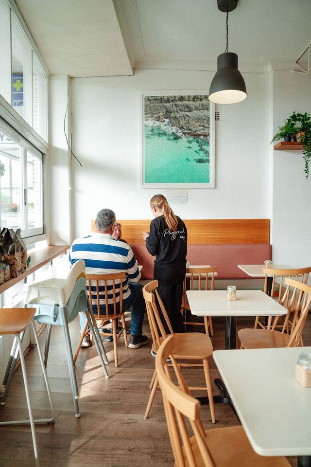A man and a woman are sitting at tables in a restaurant.