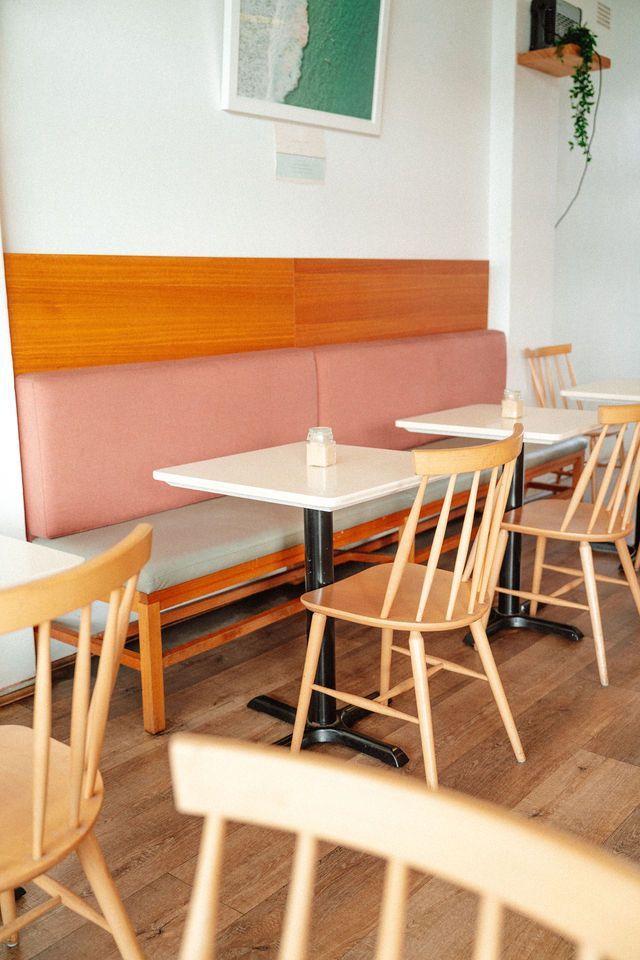A row of wooden chairs and tables in a restaurant.