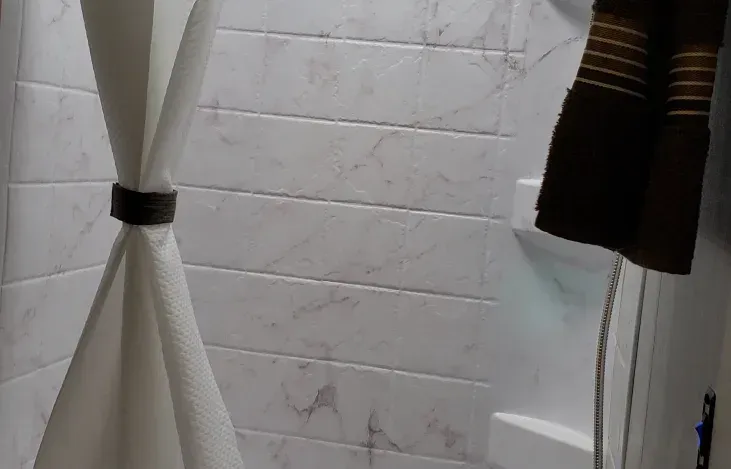 A bathroom with a shower and a towel hanging on the wall.