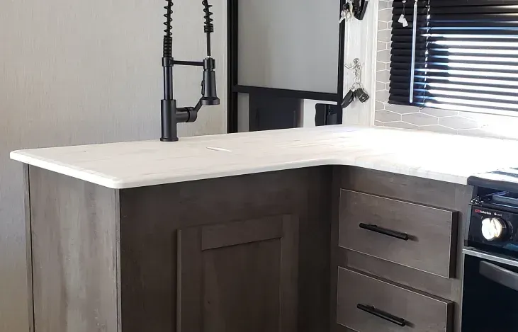 A kitchen with a sink , stove , refrigerator and cabinets.
