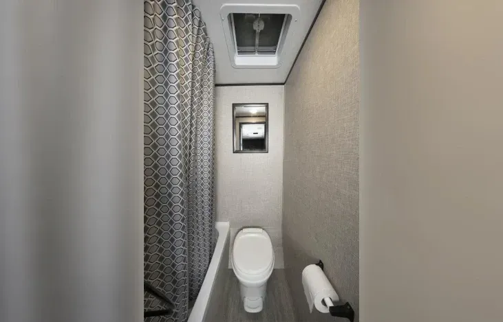 A bathroom with a toilet , shower curtain , and ceiling fan.