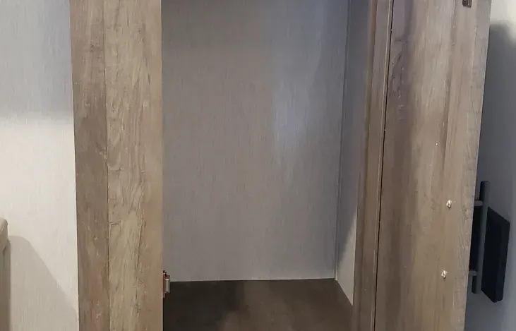 A closet with a wooden door and a wooden floor in a room.