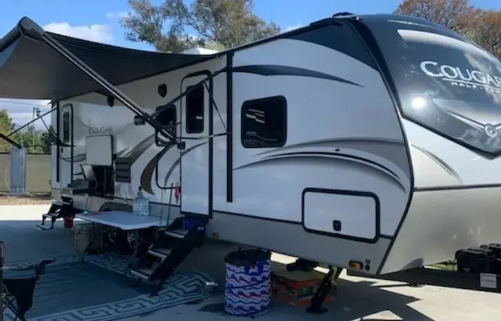 a white and black rv is parked in a parking lot .