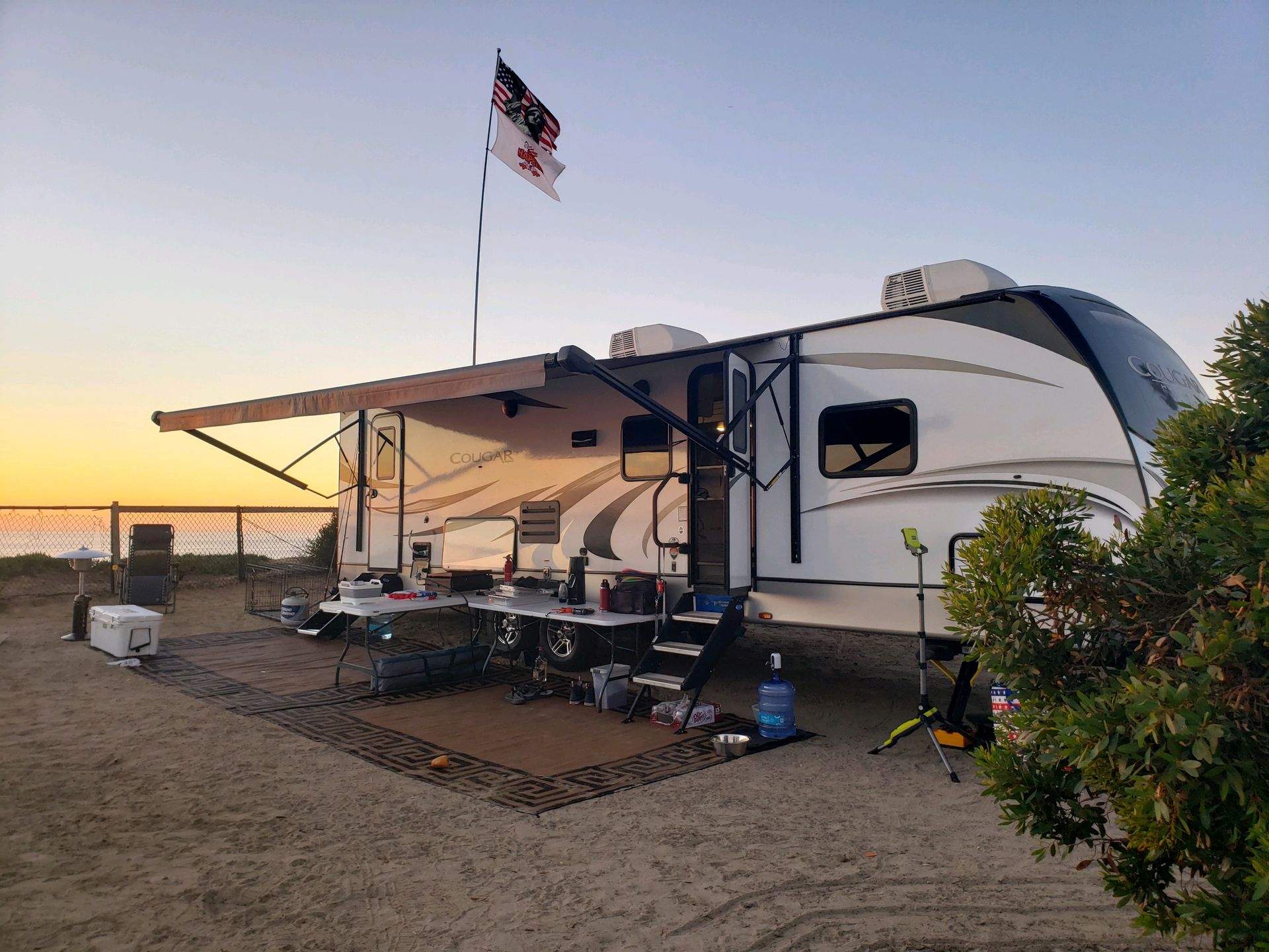 a rv is parked on the beach at sunset .