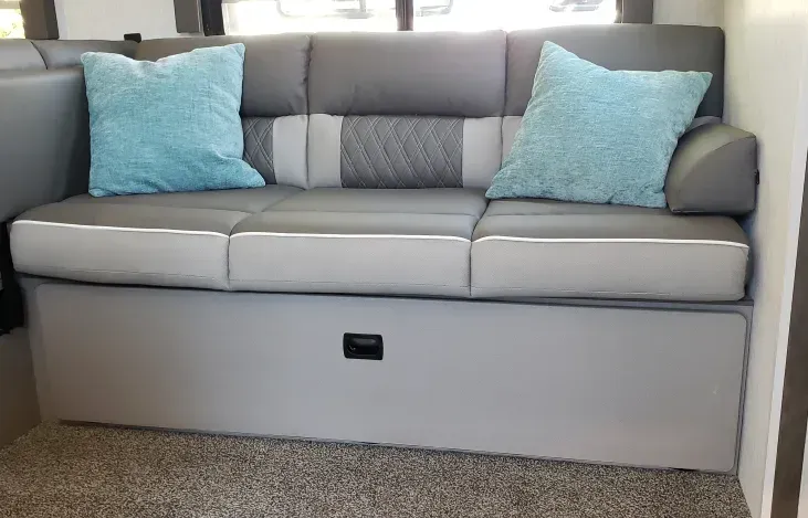 A gray and white couch with blue pillows in a living room.