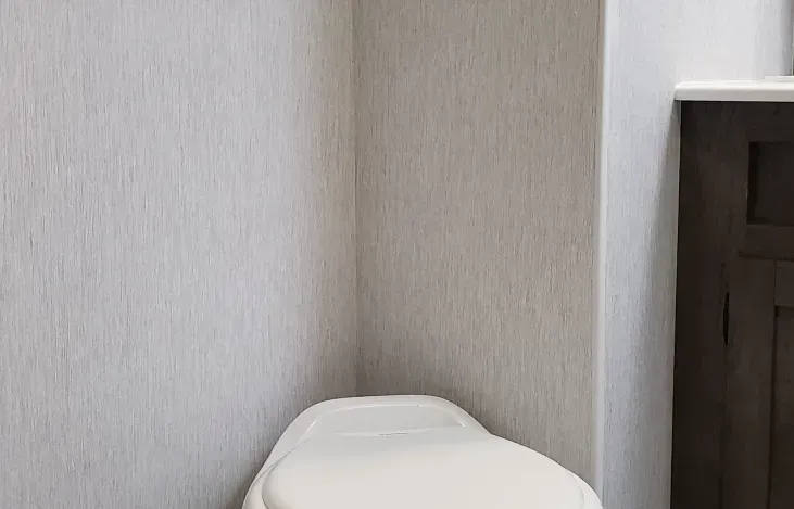 A toilet is sitting in a corner of a bathroom next to a wall.