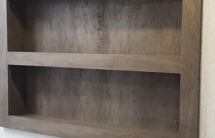 A wooden shelf with two shelves is hanging on a wall.
