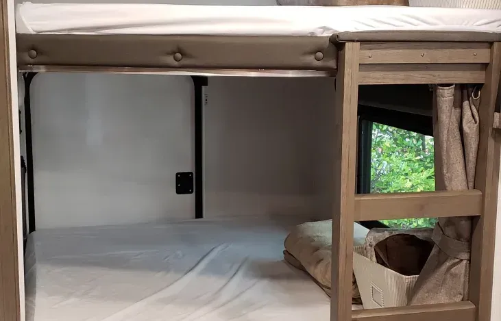 a bunk bed with a ladder and a window in a camper .