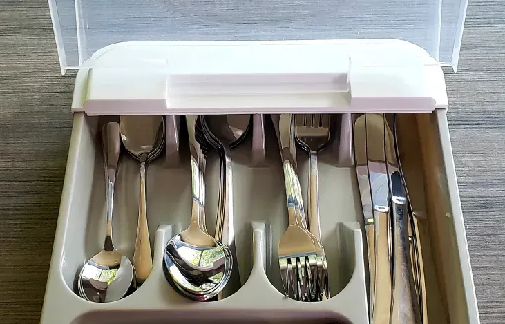 A silverware tray with spoons , forks and knives in it
