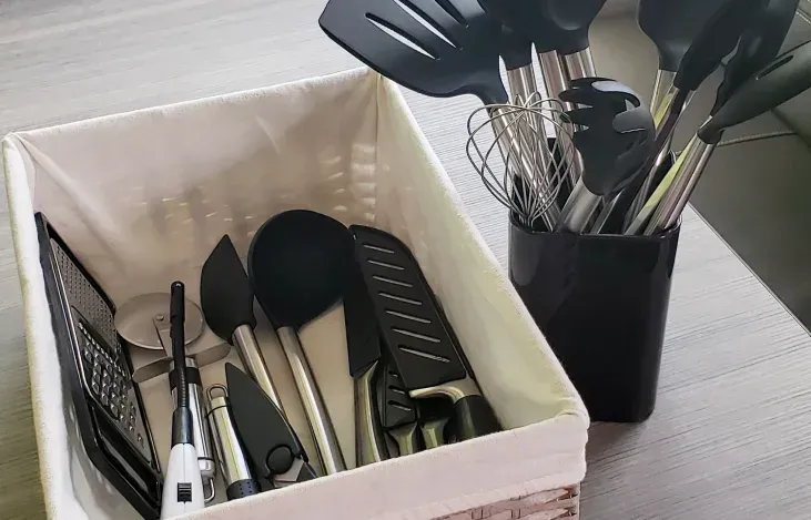 A basket filled with kitchen utensils is sitting on a table.