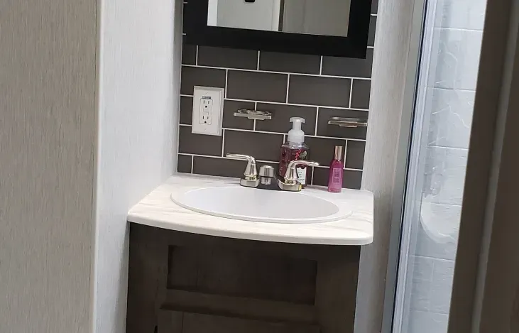 A bathroom with a sink , mirror and shower curtain.