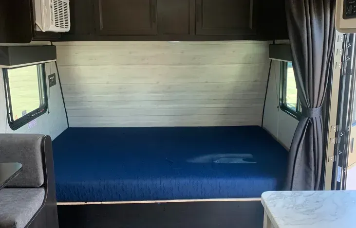 The inside of a camper with a blue mattress and a couch.