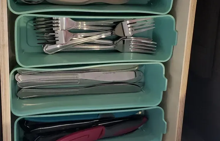 A drawer filled with utensils including forks , knives , and spoons.