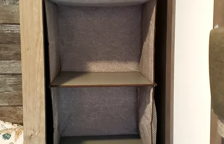 an empty shelf is sitting on top of a wooden shelf .