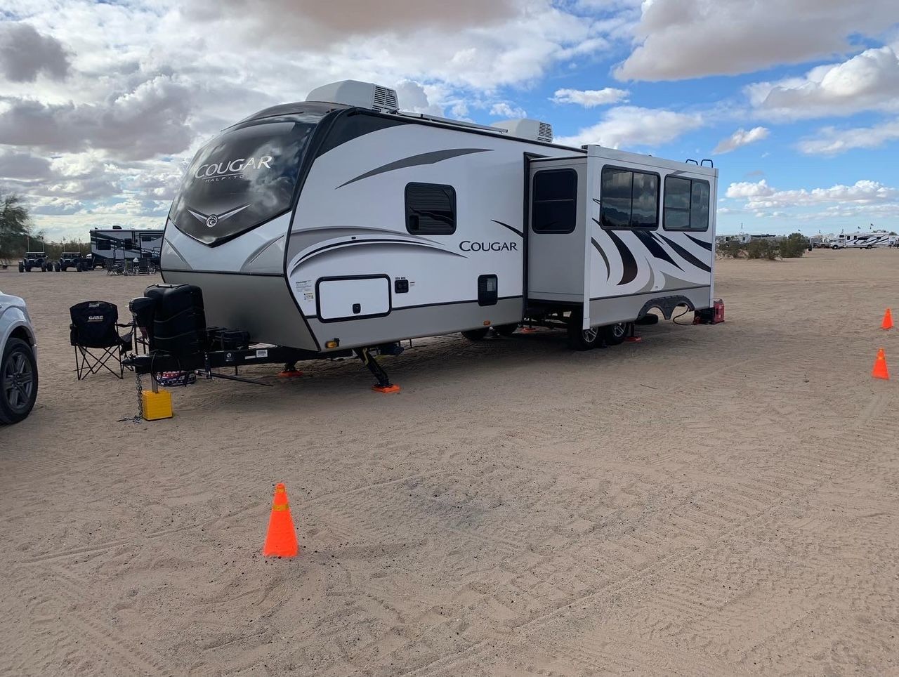 a white rv is parked in the middle of a dirt field .