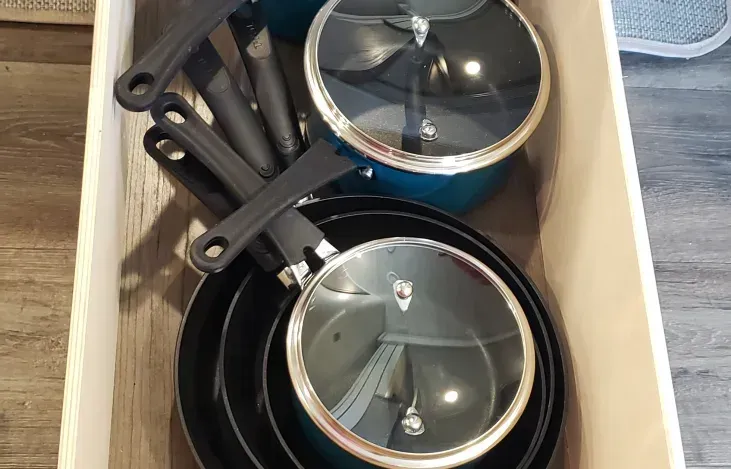 a wooden box filled with pots and pans with glass lids .