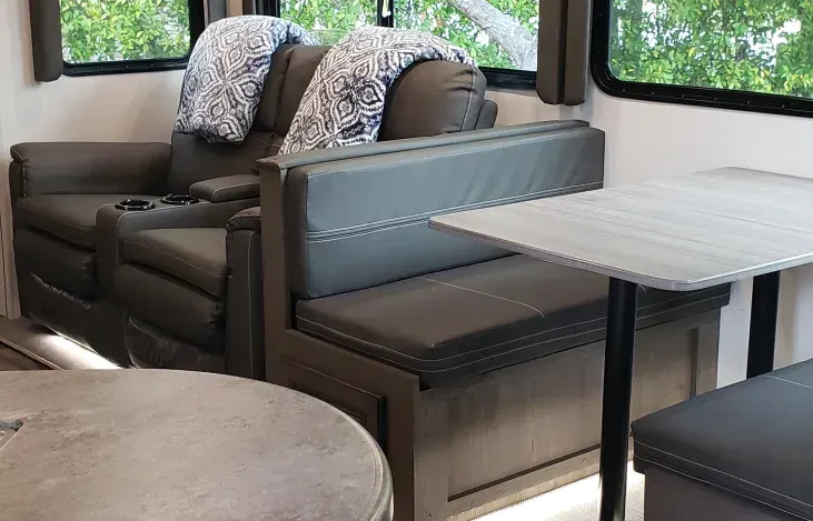 a living room in a rv with a couch , table and benches .