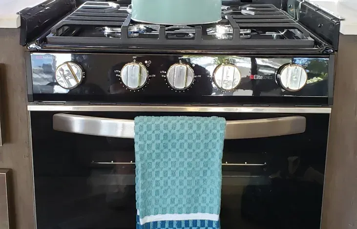 A towel is hanging from the door of a stove.