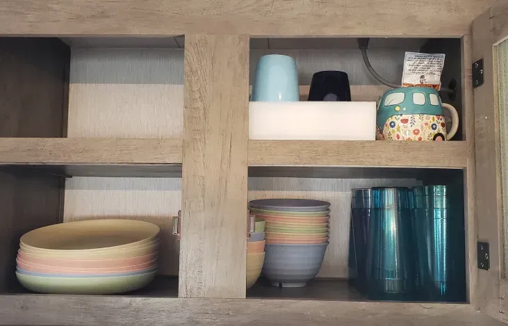 A kitchen cabinet filled with bowls , cups , and glasses.