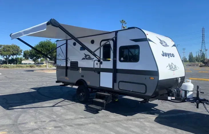 a small trailer with an awning is parked in a parking lot .
