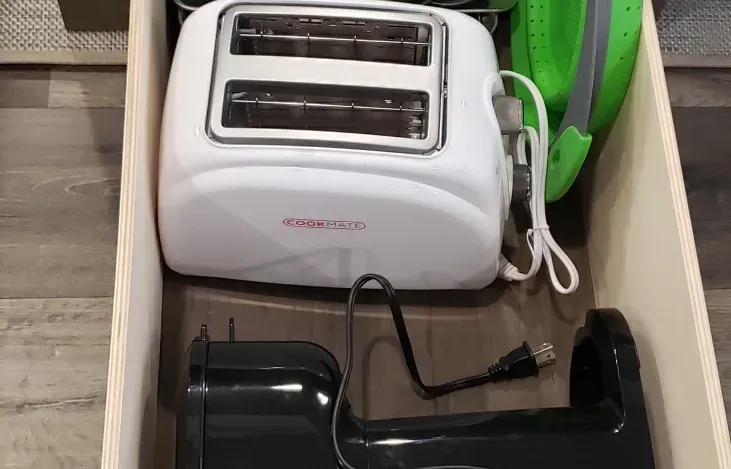 a toaster and a mixer are in a drawer .
