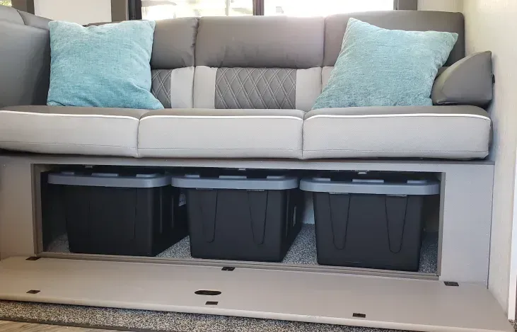 A couch with three storage bins underneath it in a rv.