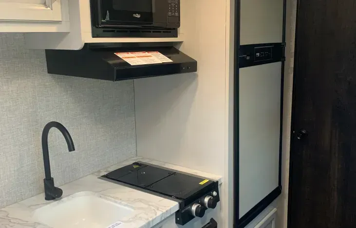 A kitchen with a sink , stove , microwave and refrigerator.