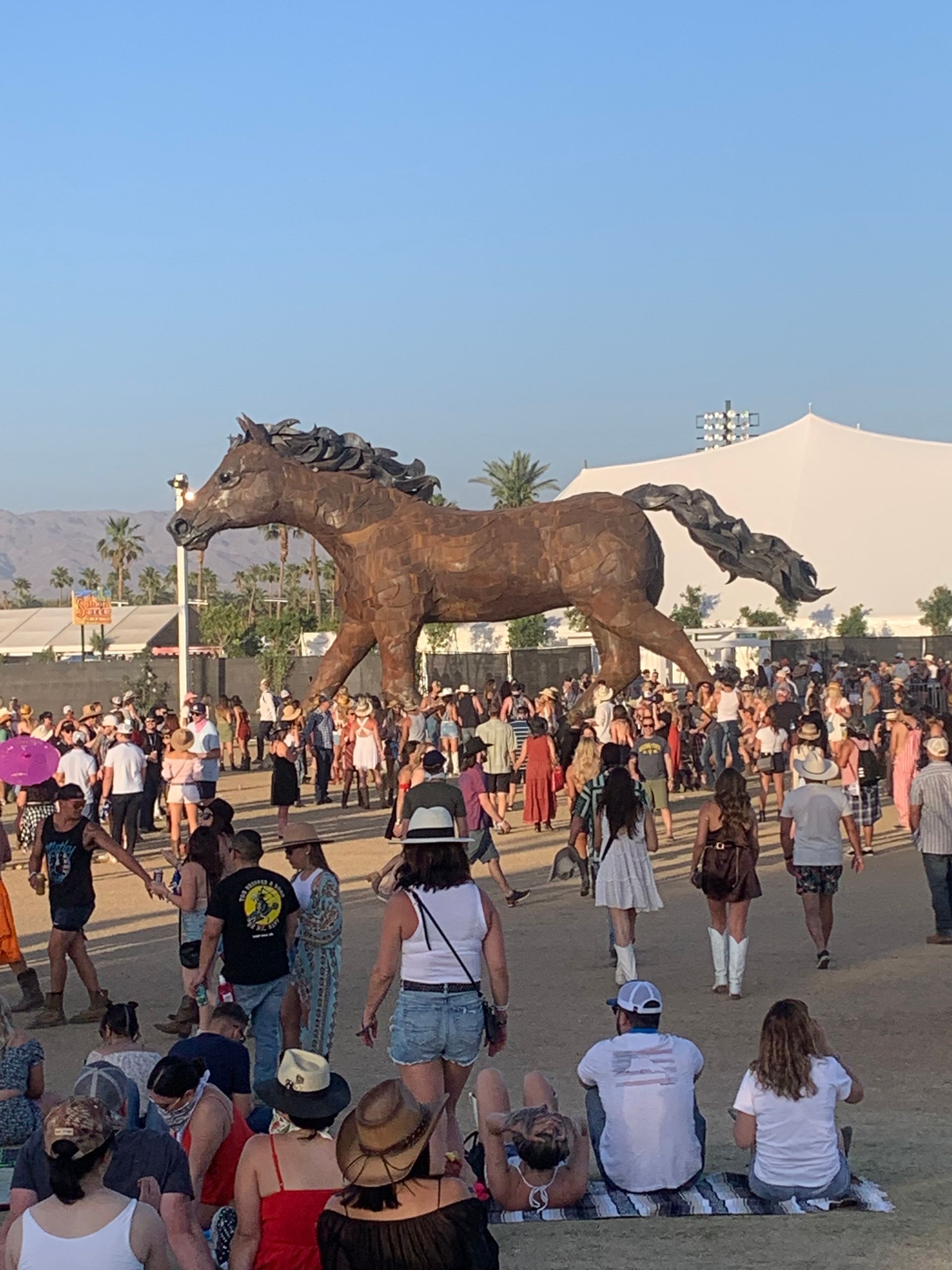a crowd of people are gathered around a statue of two horses .